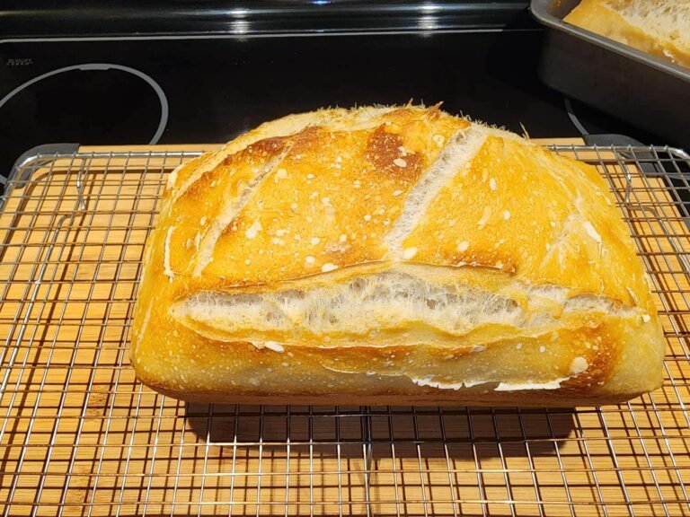 Golden crust baked sourdough bread cooling on wire rack.